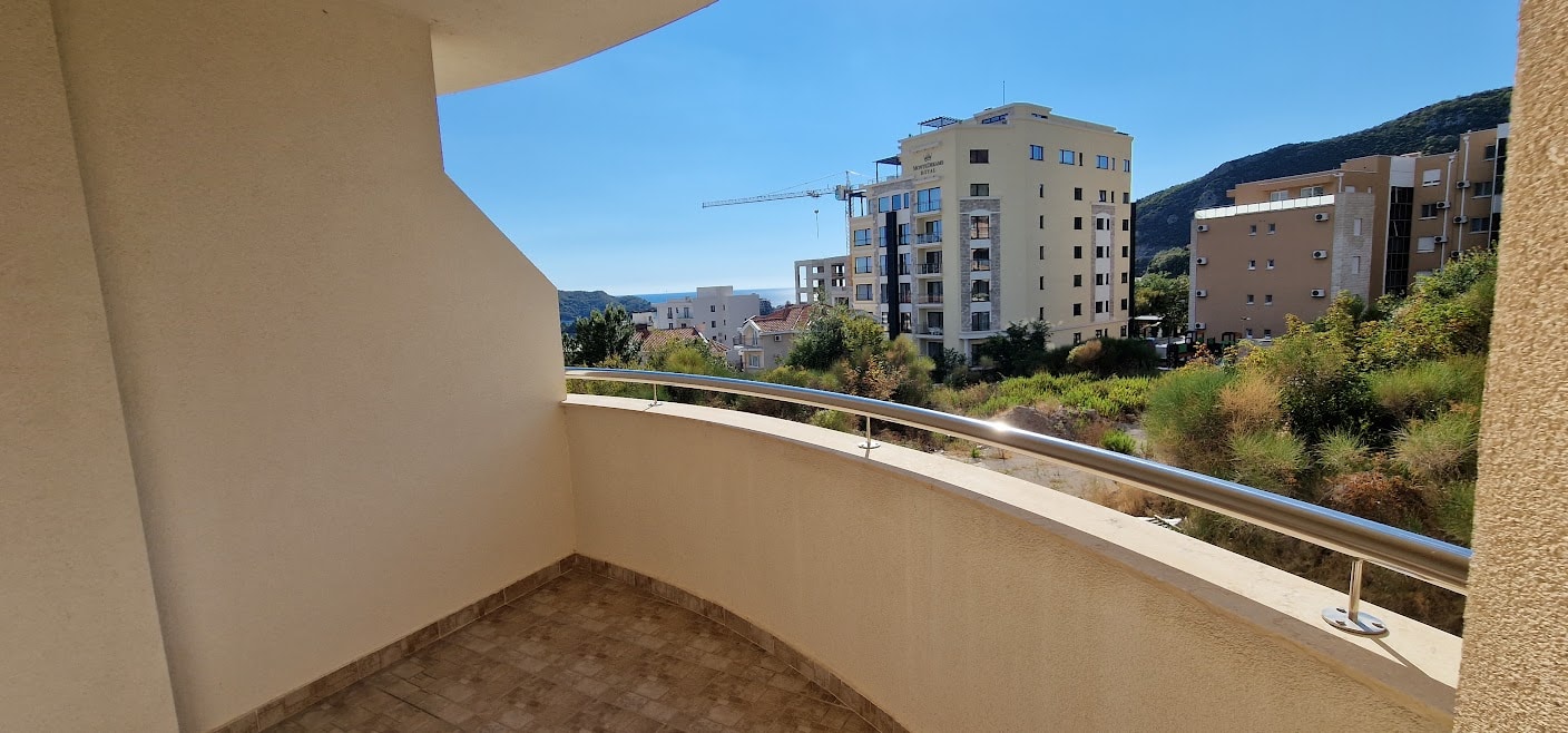 View from the apartment balcony in Bečići, Budva Riviera, Montenegro: a panorama of the sea, mountains, and modern development.