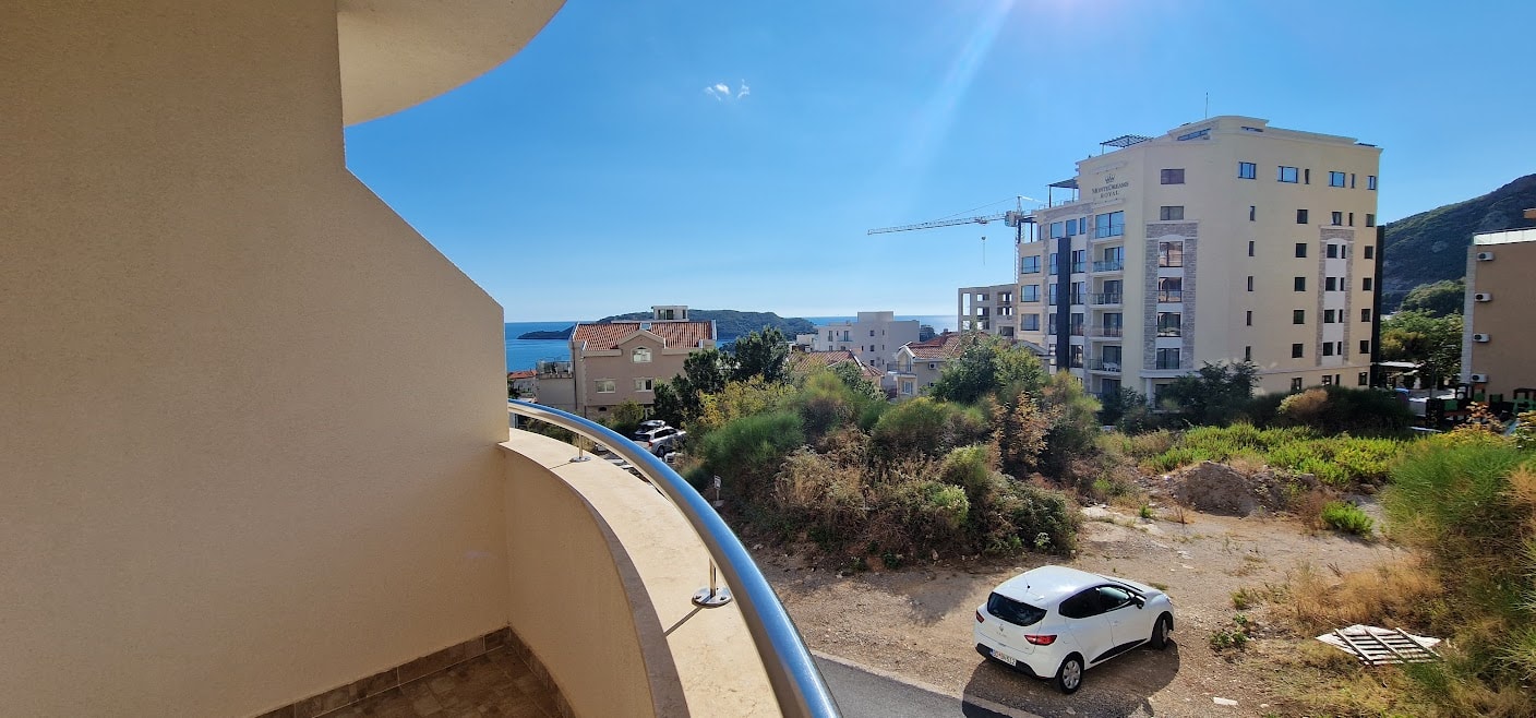 View from the apartment balcony in Bečići, Budva Riviera, Montenegro: panoramic sea view, residential complex, and mountains.