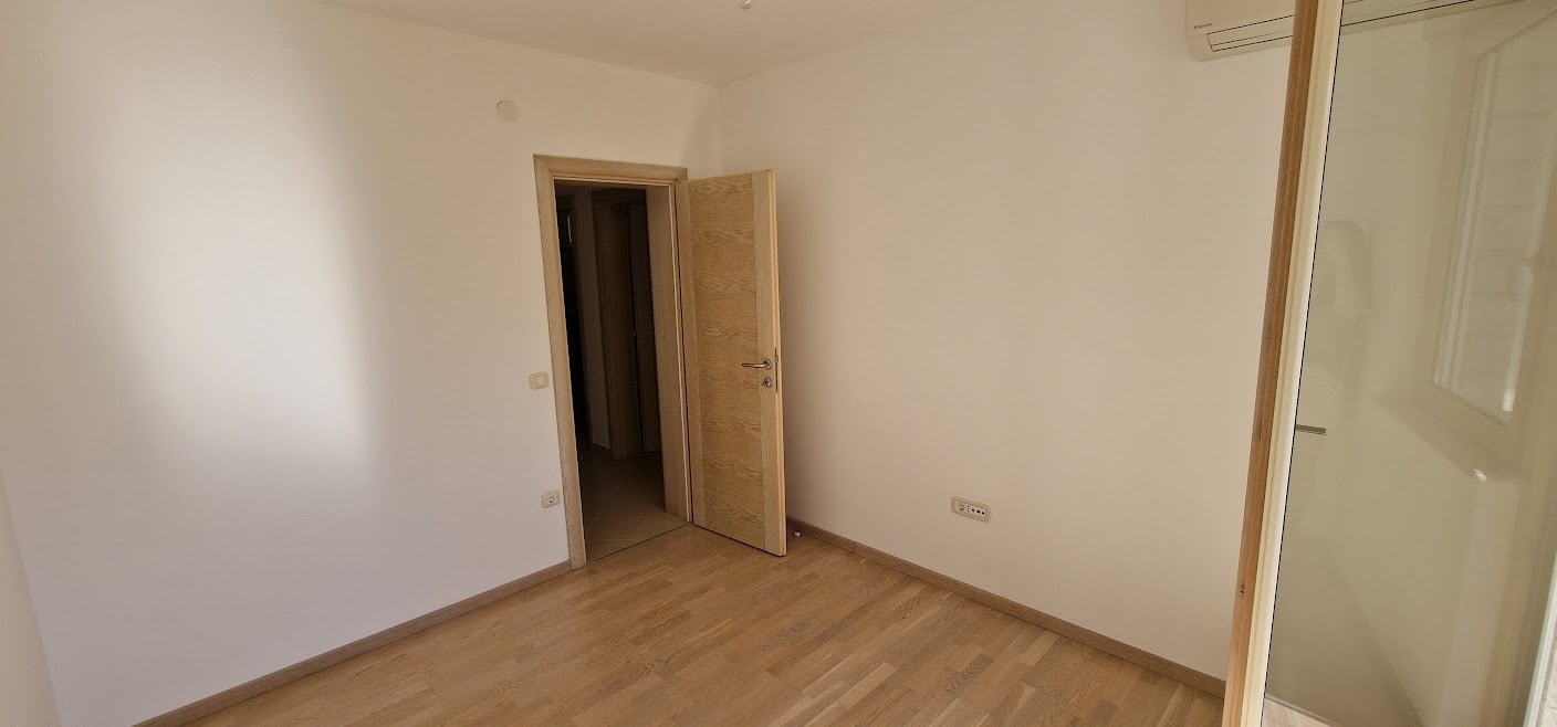 Bright bedroom with parquet flooring and an interior door in an apartment in Becici, Budva Riviera, Montenegro.