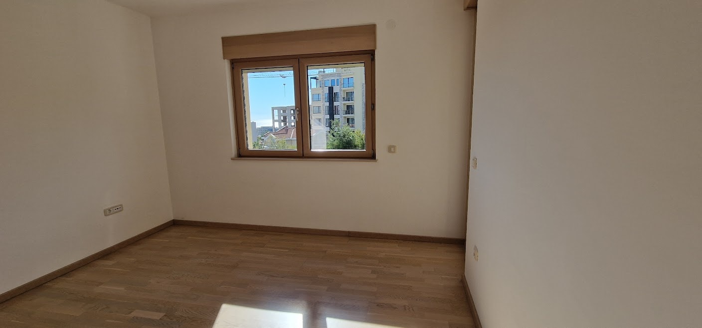Bright bedroom with parquet flooring and city view in an apartment in Becici, Budva Riviera, Montenegro.