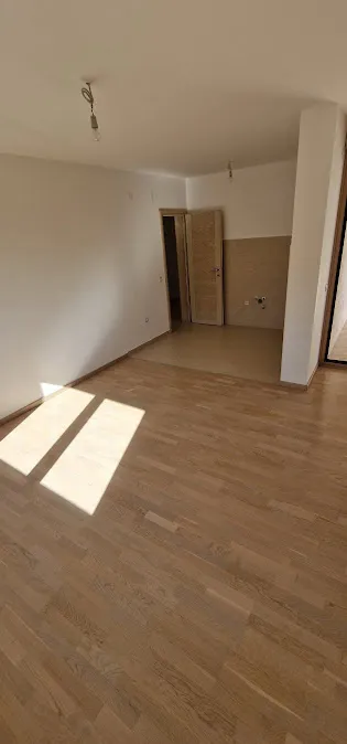Empty room with laminate flooring and white walls, featuring a doorway and temporary ceiling wiring.