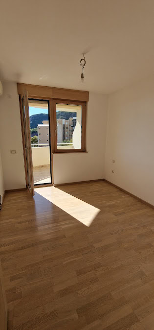Bright bedroom with parquet flooring and access to the balcony in an apartment in Becici, Budva Riviera, Montenegro.
