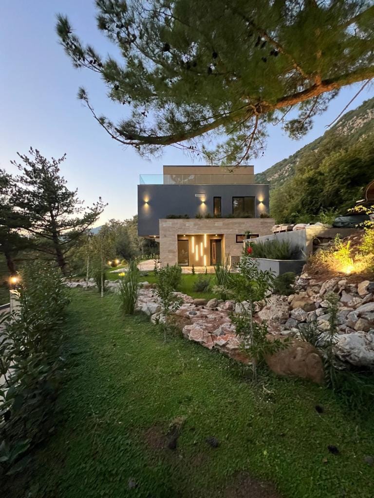 Modern villa in Kavac, Montenegro: stone-clad facade, landscaping, and evening lighting.