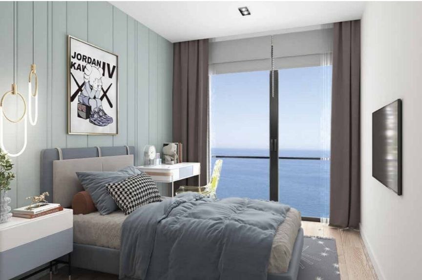 Modern bedroom with sea view in a residential complex in Bar, Montenegro: double bed, desk, and panoramic windows.