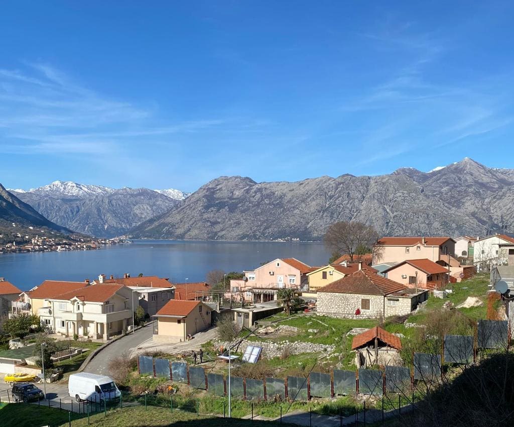 Panoramic view of Kotor Bay and the mountains from a residential complex in Dobrota, Montenegro: houses with red roofs.