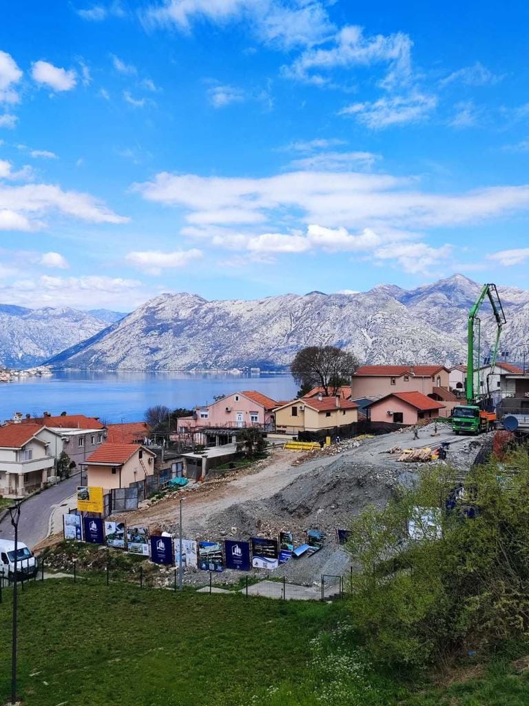 Construction site of a residential complex in Dobrota, Montenegro, with panoramic views of the Bay of Kotor and the mountains.