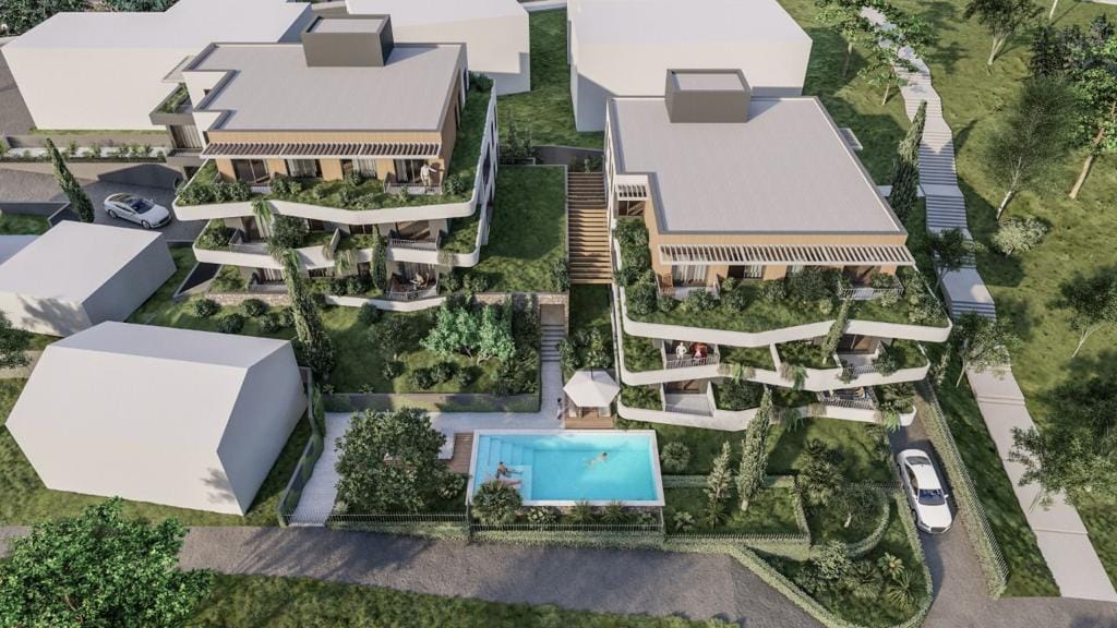 Aerial view of a residential complex in Dobrota, Montenegro: modern buildings with terraces, landscaping, and a shared swimming pool.