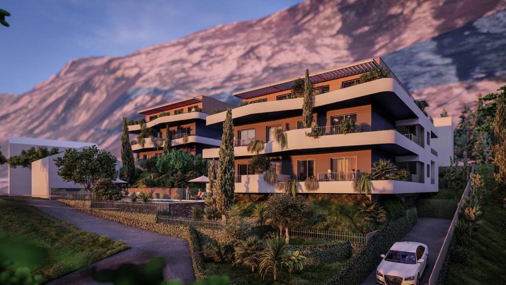 Modern residential complex in Dobrota, Montenegro: terraces, pool, and panoramic mountain views in the sunset light.