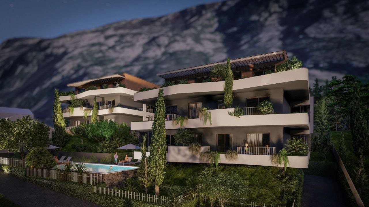 Modern residential complex in Dobrota, Montenegro: view of the building with terraces, greenery, and a swimming pool in the evening.