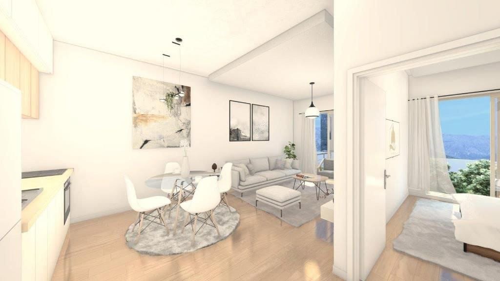 Modern living room with kitchen in Dobrota residential complex, Montenegro: bright interior, dining area, and mountain view from the window.