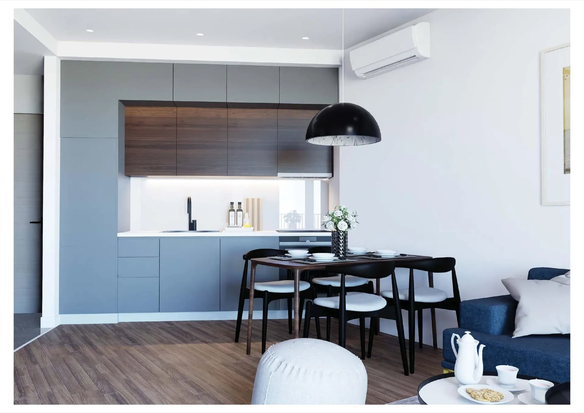 Open plan space featuring grey kitchen cabinets, a dining table with black chairs, and a blue sofa.
