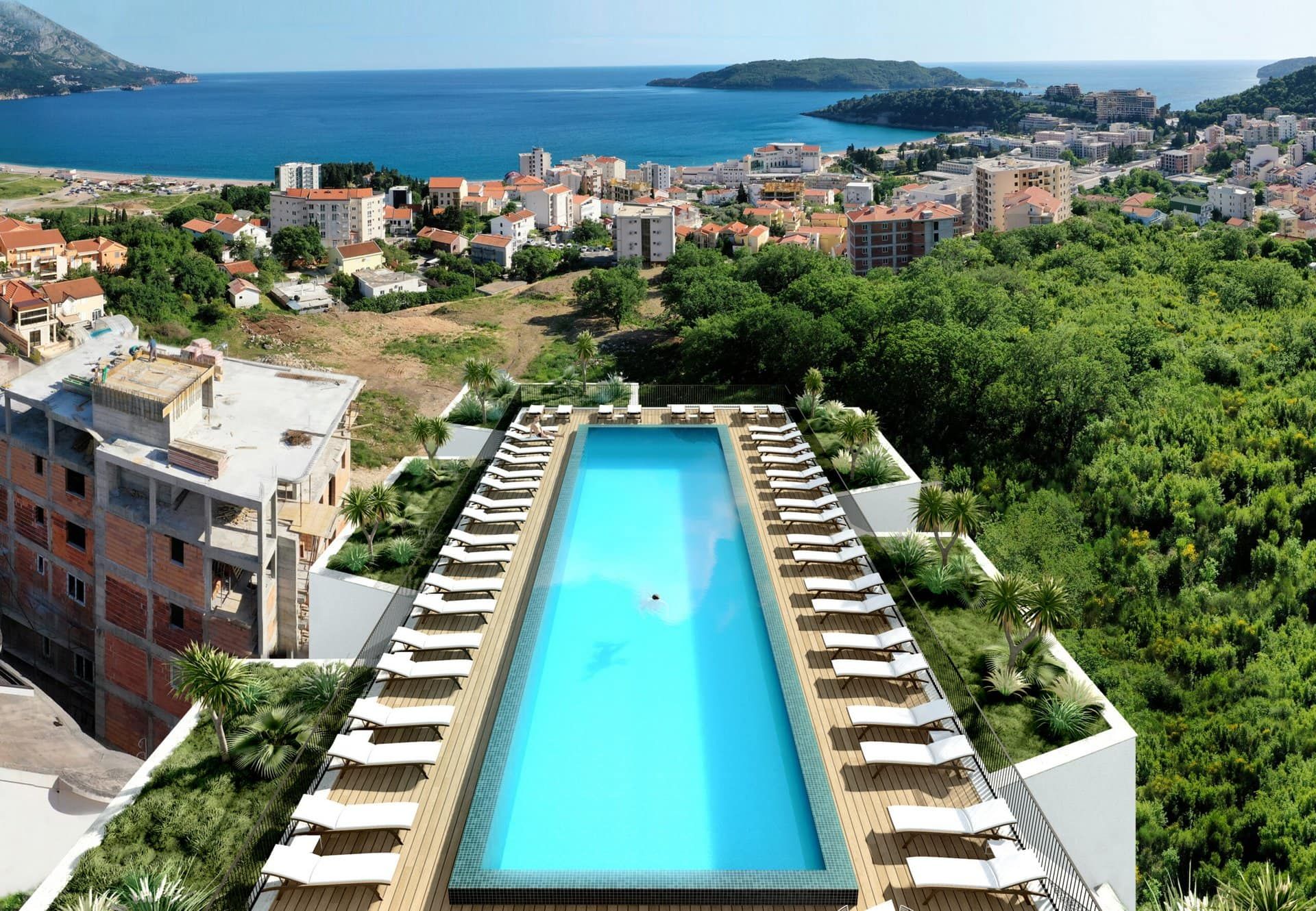Rooftop panoramic pool in a residential complex in Bečići, Montenegro, with sun loungers and sea and city views.