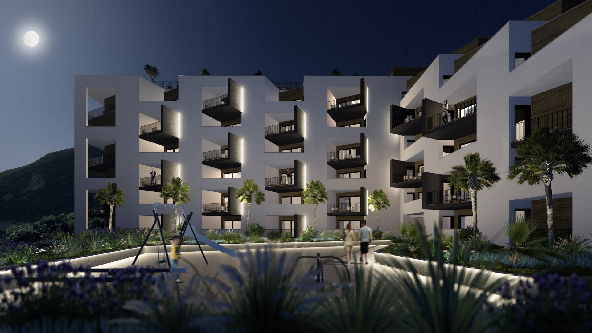 Modern residential complex in Bečići, Montenegro: illuminated night facade with balconies and a playground in the courtyard.