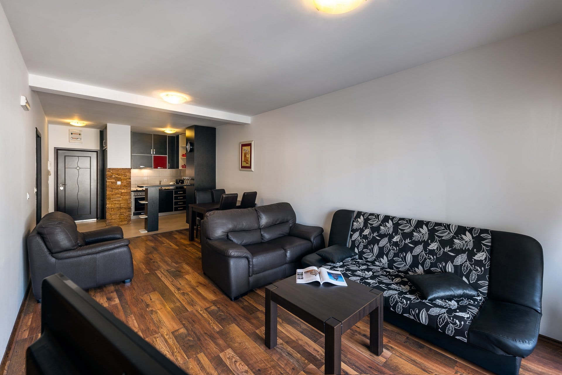 Living room with leather furniture and kitchen in an apartment in Budva, Montenegro: modern interior with laminate flooring and dining area