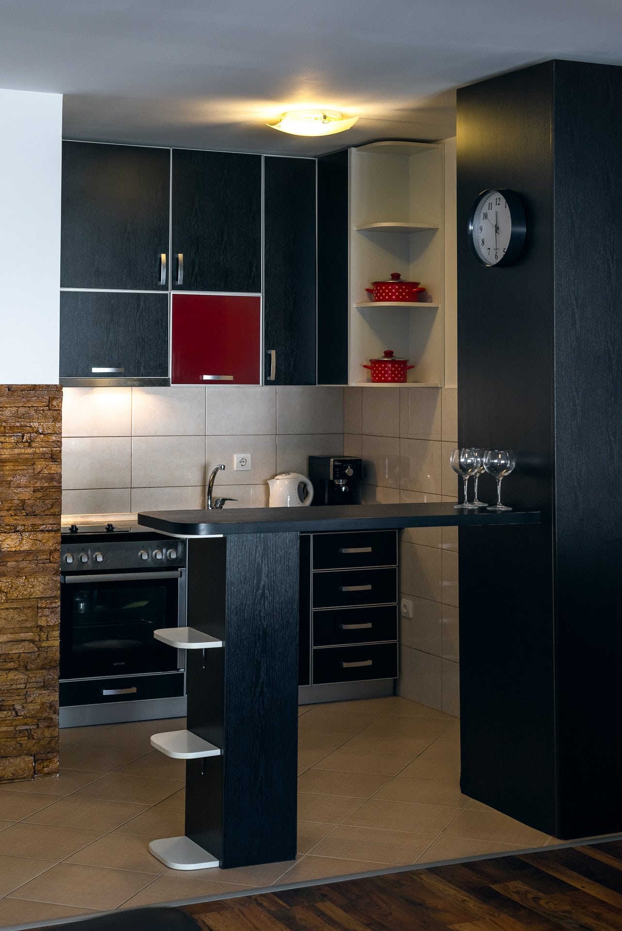 Modern kitchen with a breakfast bar in an apartment in Budva, Montenegro: black cabinetry, tile, and decorative stone.
