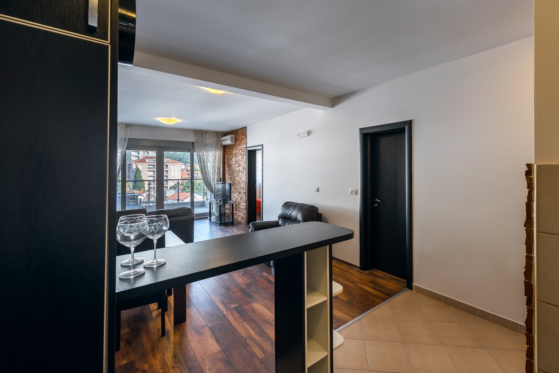 Living room with a bar counter and access to the balcony in an apartment in Budva, Montenegro: modern interior, dark furniture.