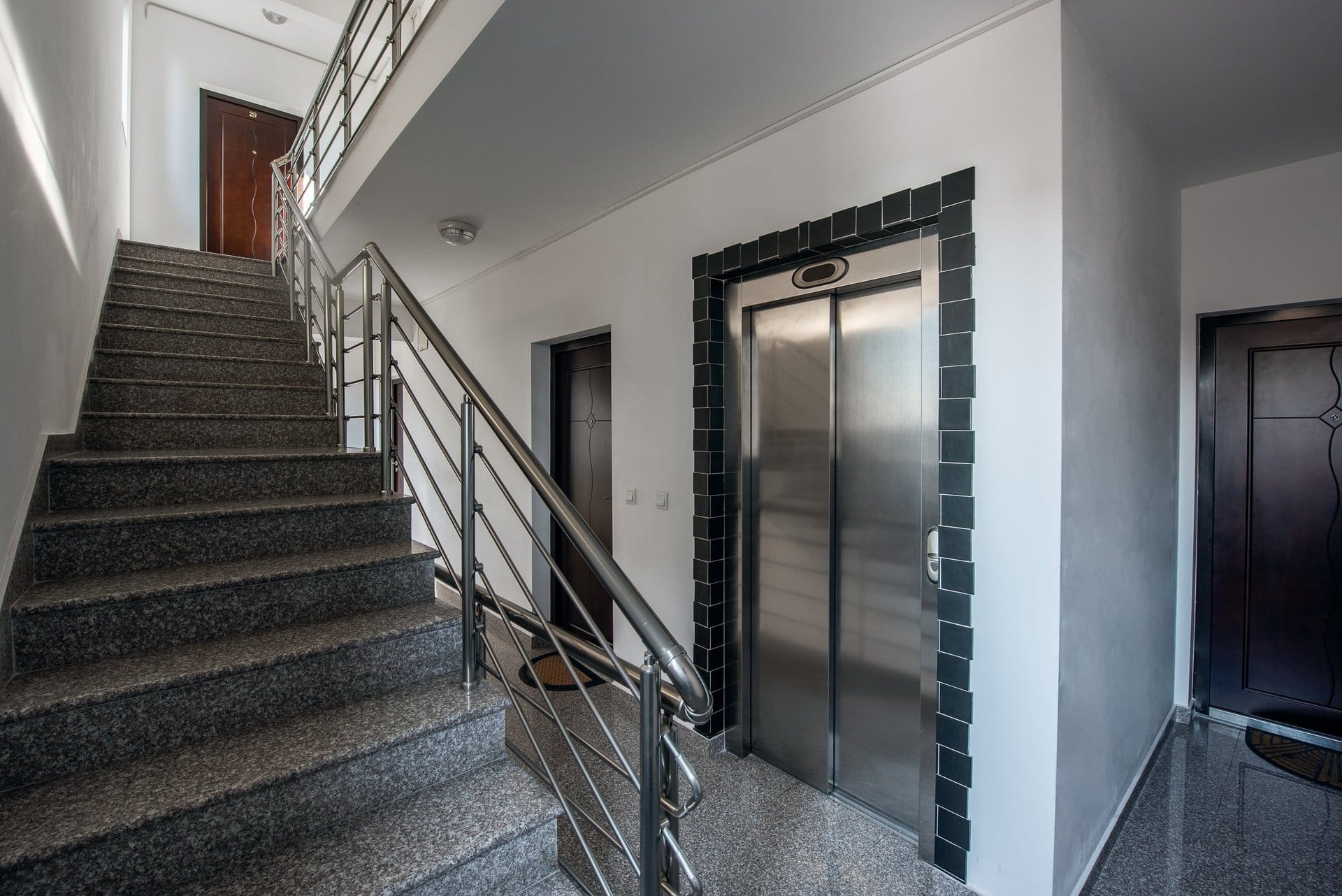 Modern entrance hall with elevator and granite staircase in a residential building in Budva, Montenegro.