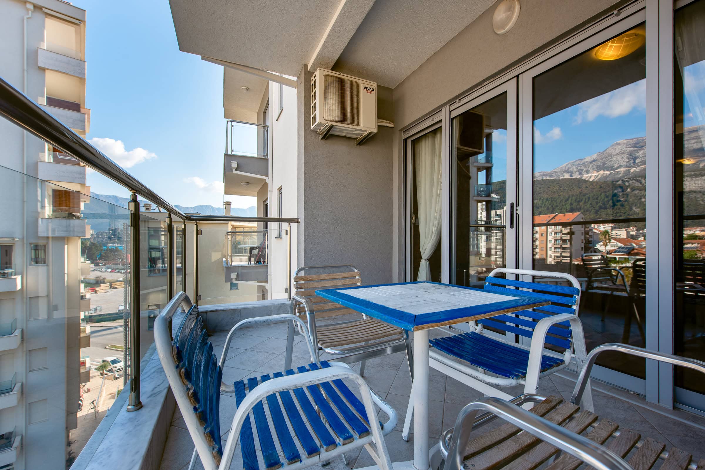 Balcony with furniture in an apartment in Budva, Montenegro, with panoramic views of the mountains and the city.