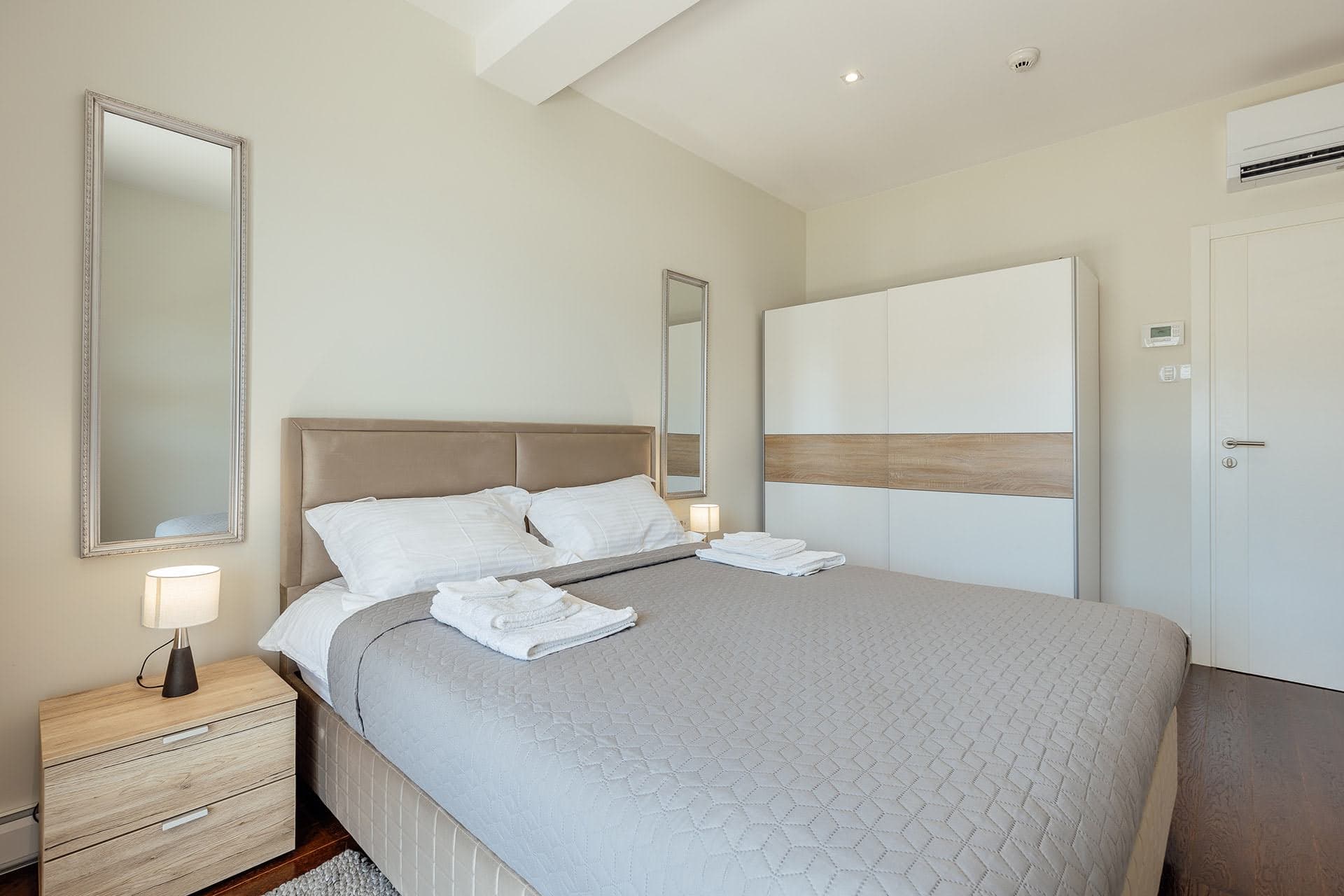Bright bedroom with a double bed and wardrobe in the Kumbor residential complex, Montenegro: modern interior and cozy atmosphere.
