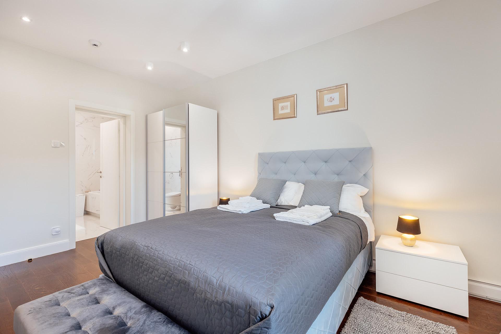Modern bedroom with a double bed and bathroom in the Kumbor residential complex, Montenegro. Bright interior, parquet flooring.