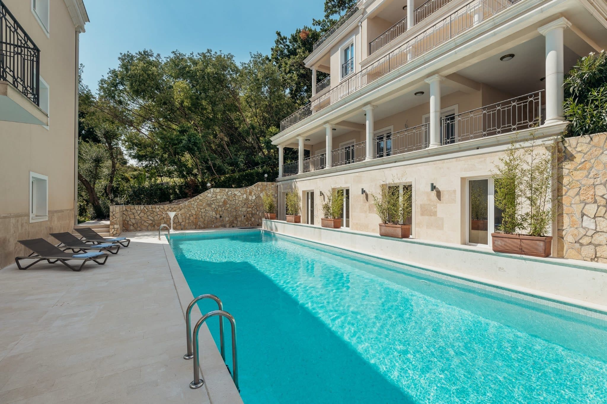An outdoor pool with sun loungers at a luxury residential complex in Kumbor, Montenegro, with stone finishes and a terrace.