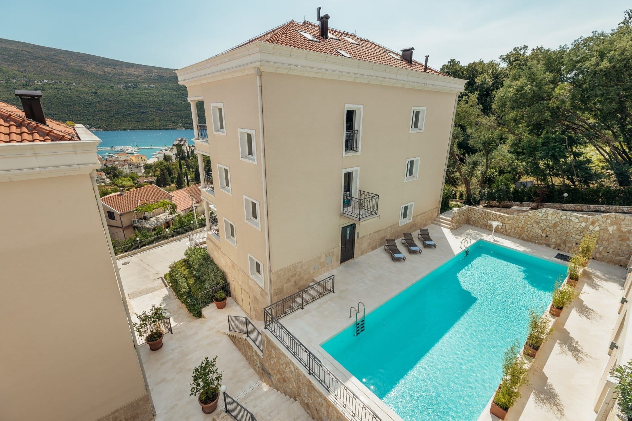 Residential complex in Kumbor, Montenegro: view of the building with a pool, terrace, and panoramic sea and mountain views.