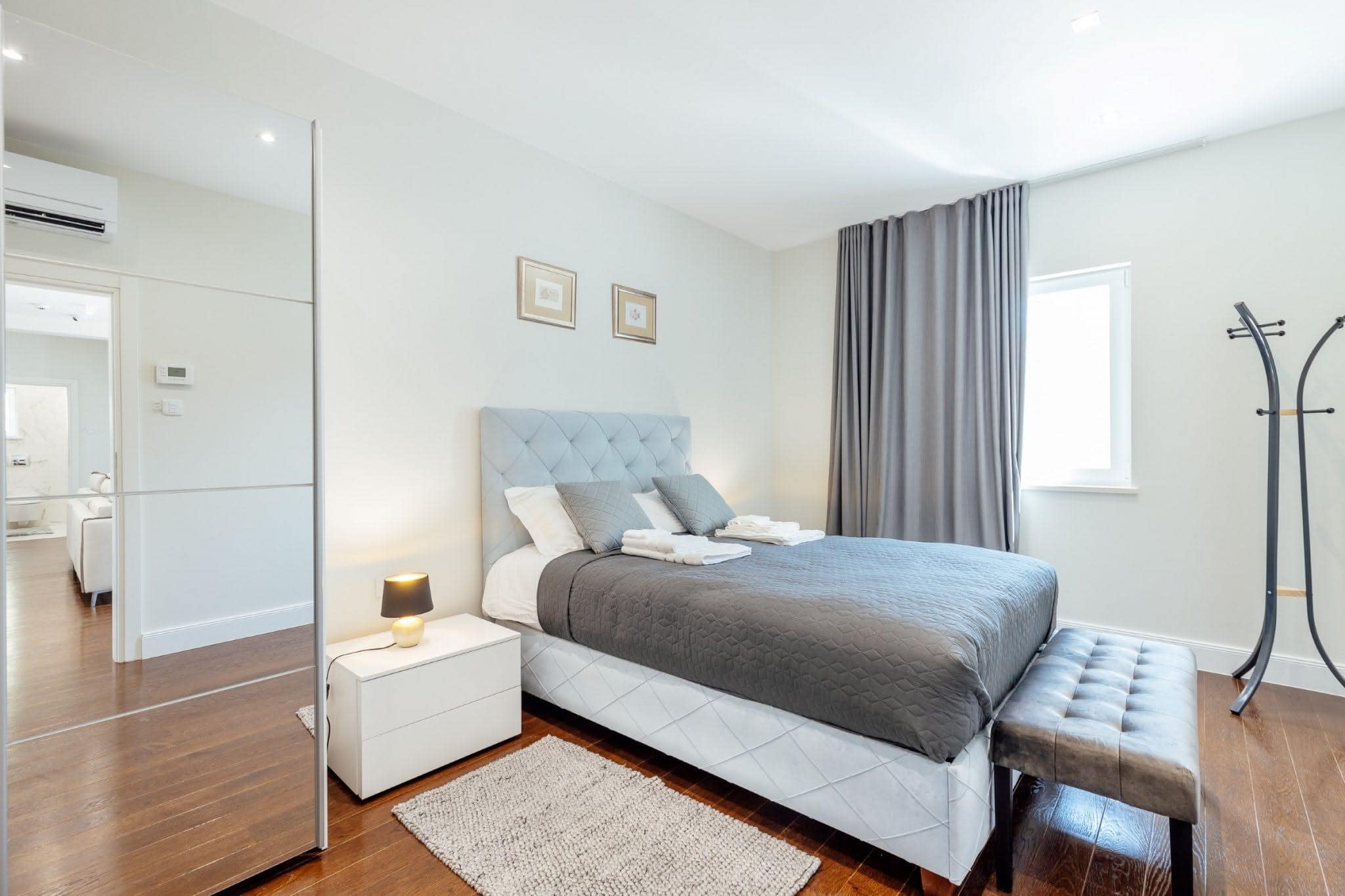 Modern bedroom with a double bed in a residential complex in Kumbor, Montenegro: bright interior, parquet flooring, and a mirrored wardrobe.