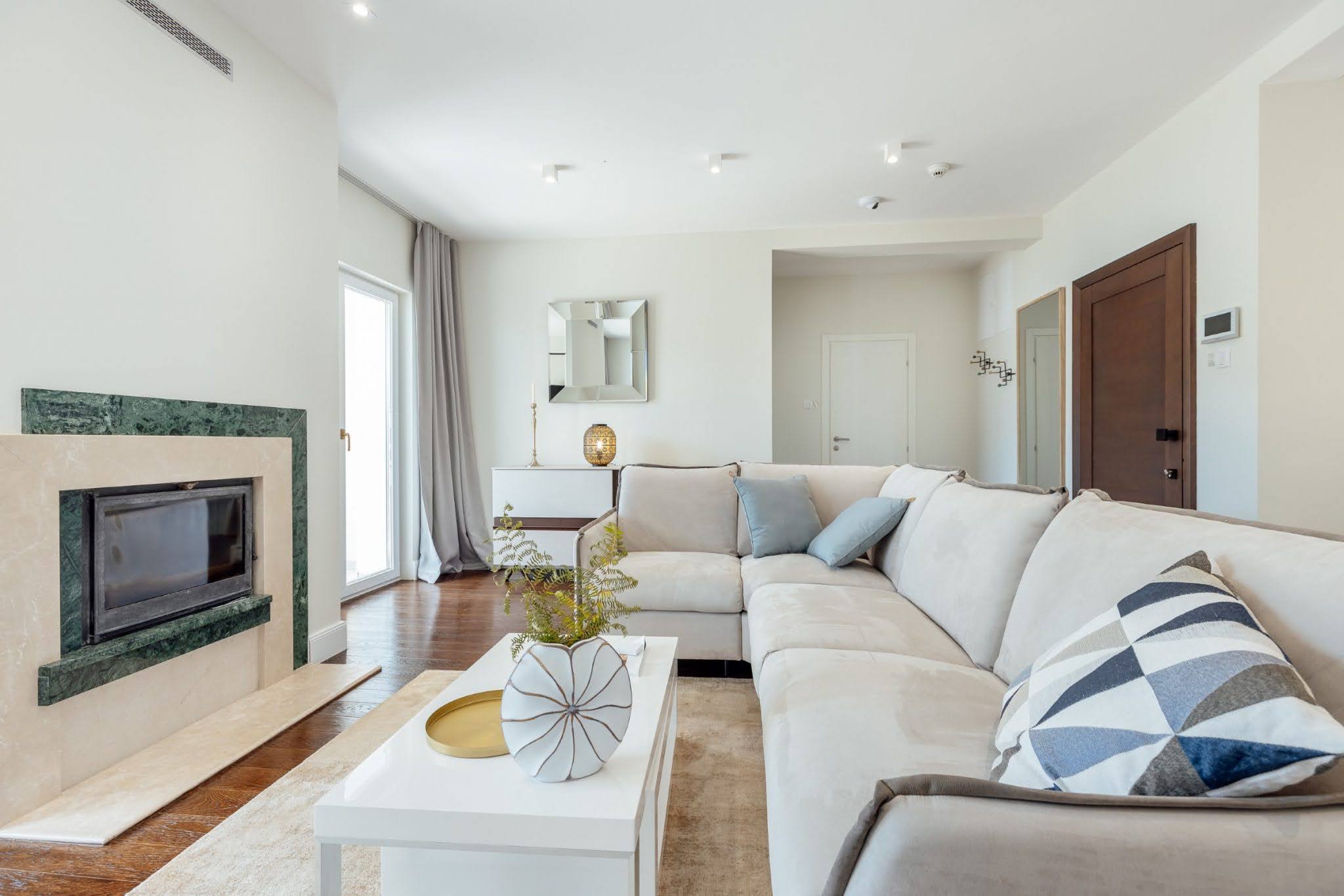 Bright living room with a fireplace and corner sofa in a residential complex in Kumbor, Montenegro. Modern interior.
