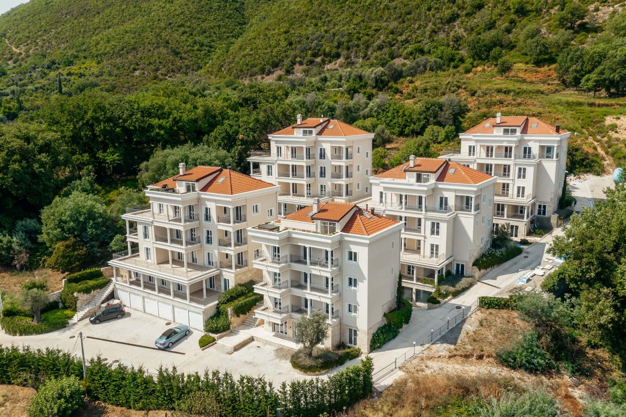 Residential complex in Kumbor, Montenegro: modern apartment buildings with terraces and tiled roofs in the mountains.