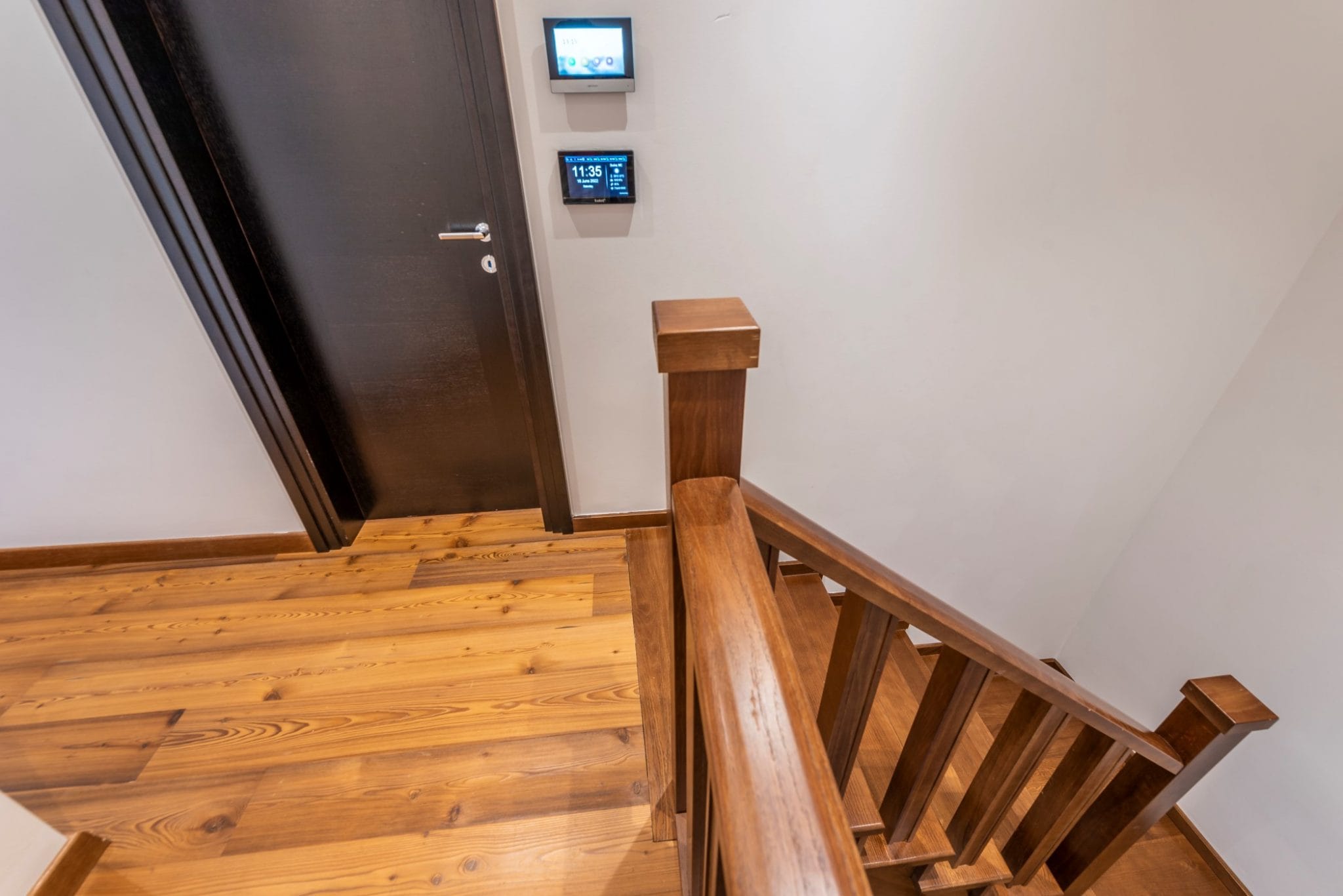 Wooden staircase and smart home system in a penthouse in Bečići, Montenegro. Modern interior with wood finishes.