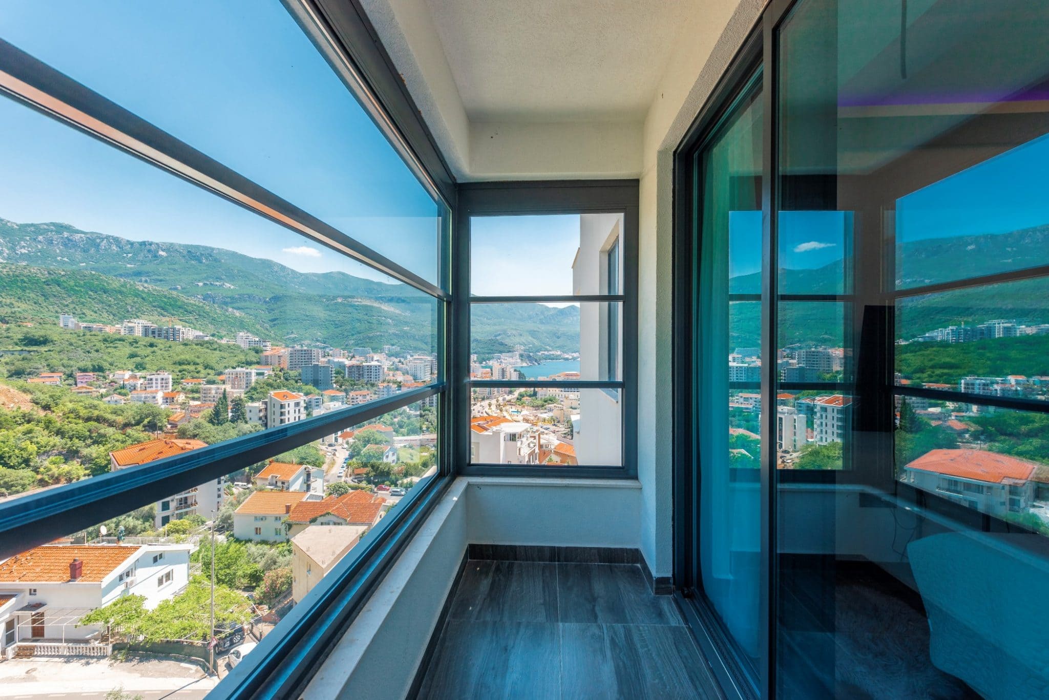 Panoramic balcony with sea and mountain views in a penthouse in Bečići, Montenegro: modern glazing and tile.