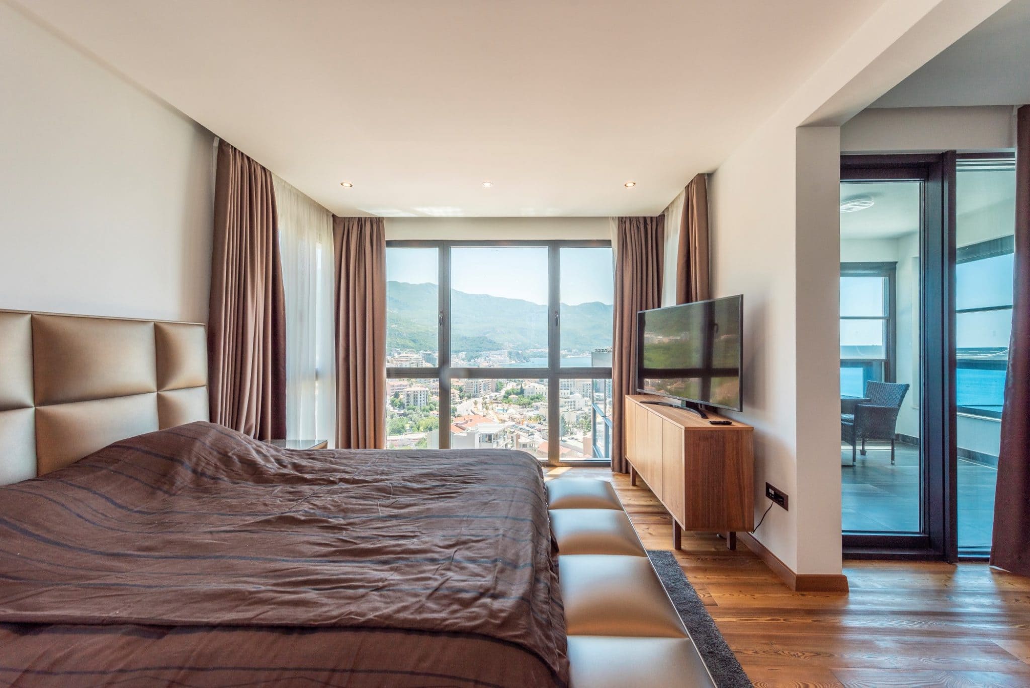 Penthouse bedroom in Bečići, Montenegro: panoramic windows with sea views, a double bed, and access to the terrace.