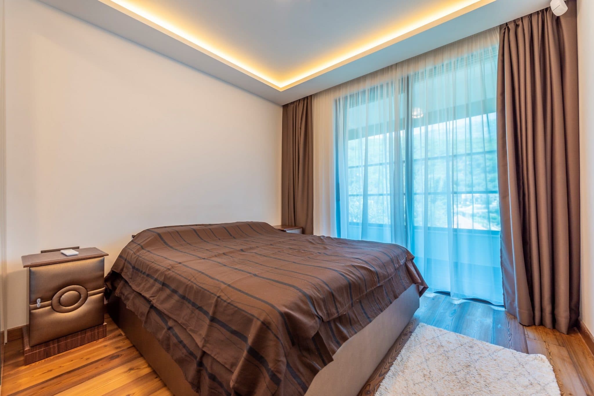 Modern bedroom in a penthouse in Bečići, Montenegro: double bed, panoramic window, and stylish lighting.