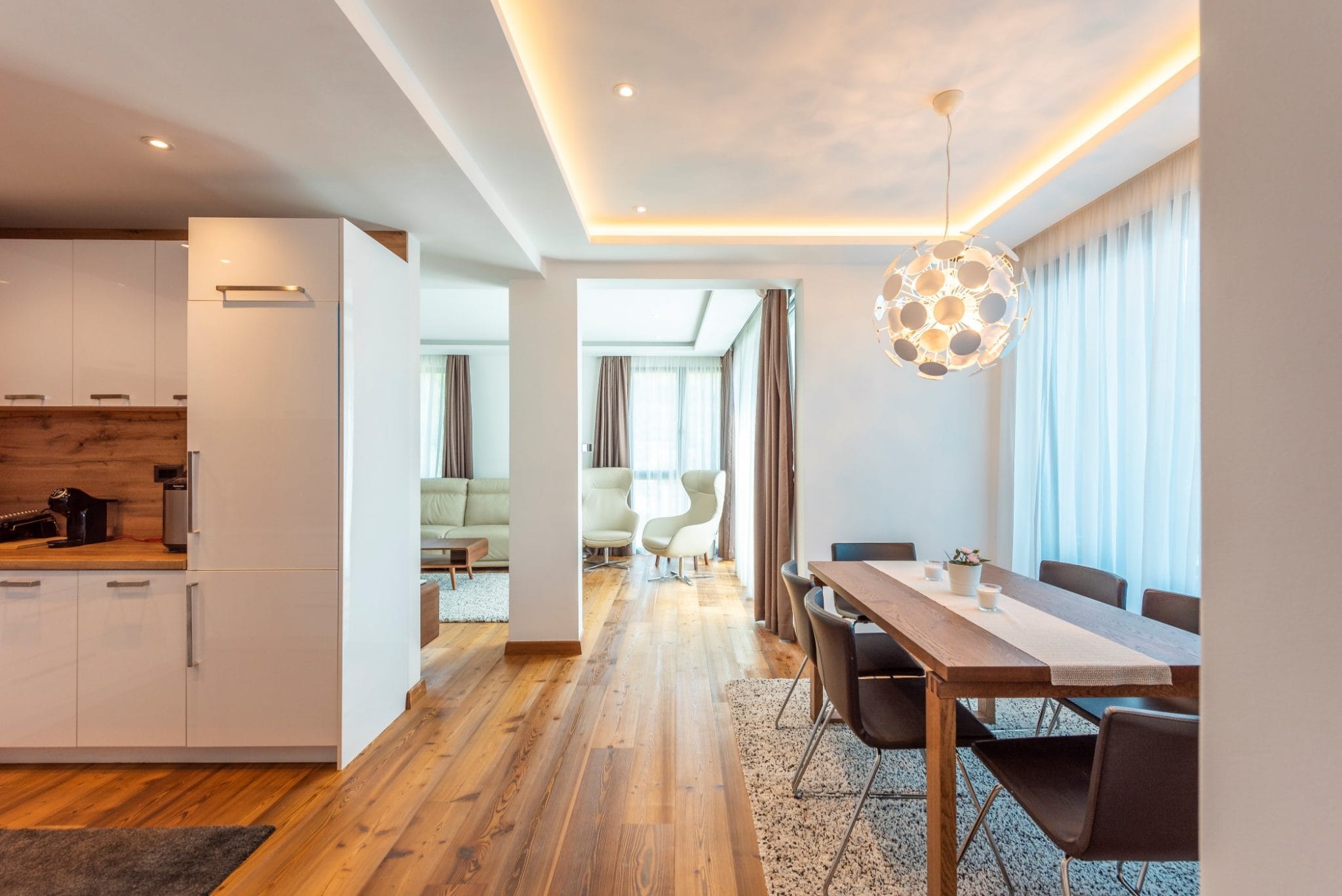 Modern living room with dining area in a penthouse, Bečići, Montenegro: bright interior, wooden floor and furniture.
