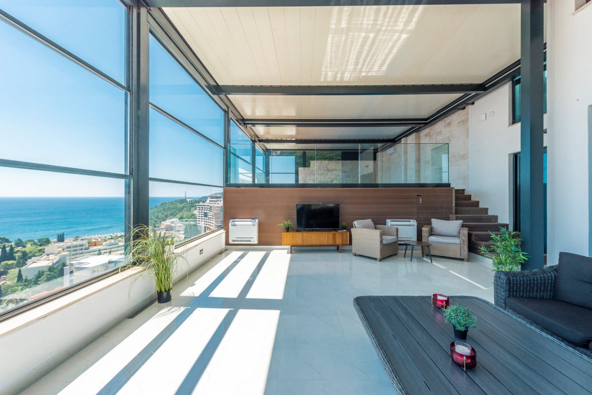 Living room in a penthouse in Bečići, Montenegro: panoramic windows with sea views, modern furniture, and a terrace.