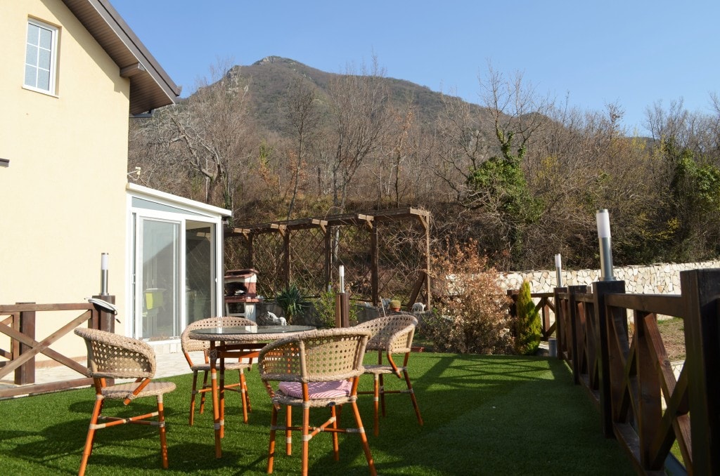 Terrace with wicker furniture and mountain views at the apartments in Bar, Montenegro: a relaxation area with artificial grass.