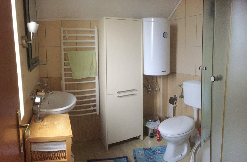 Bathroom in an apartment, Bar, Montenegro: shower cabin, boiler, cabinet, and light-colored fixtures.