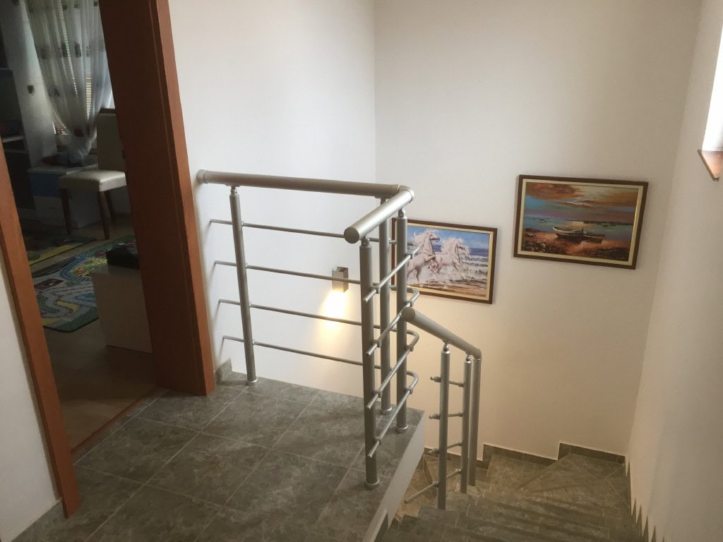 Staircase with metal railings in a two-story apartment in Bar, Montenegro, with paintings on the walls.