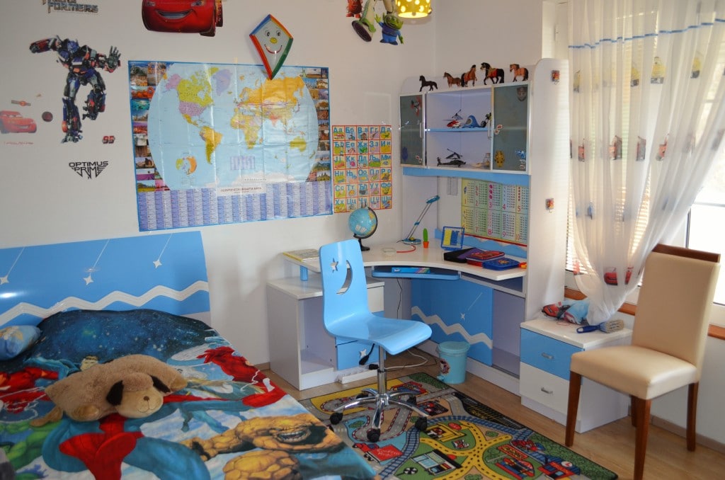 Children’s bedroom with furniture in an apartment in Bar, Montenegro: bed, desk, and a bright rug with a road.