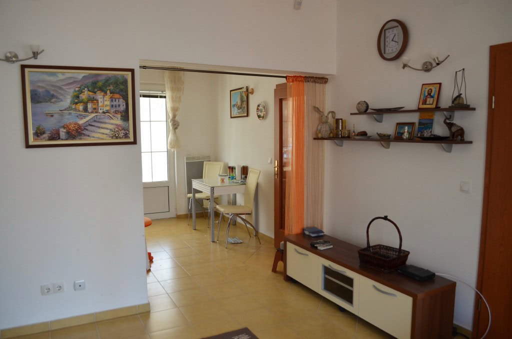 Living room in an apartment in Bar, Montenegro: a bright room with a dining area, TV stand, and wall decor.