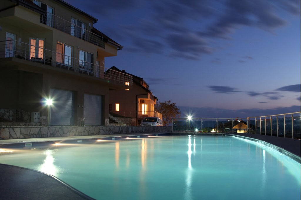 Evening pool with lighting at a modern villa in Bar, Montenegro, view of apartments with terraces.