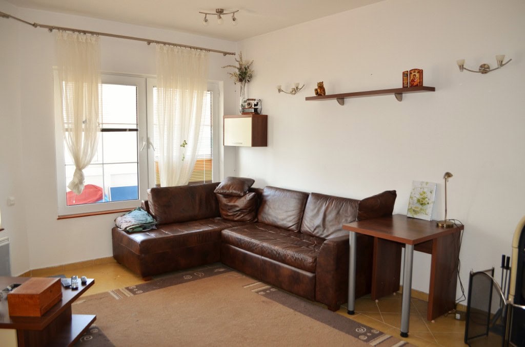 Living room with a leather corner sofa in an apartment in Bar, Montenegro: bright interior, window, and furniture.