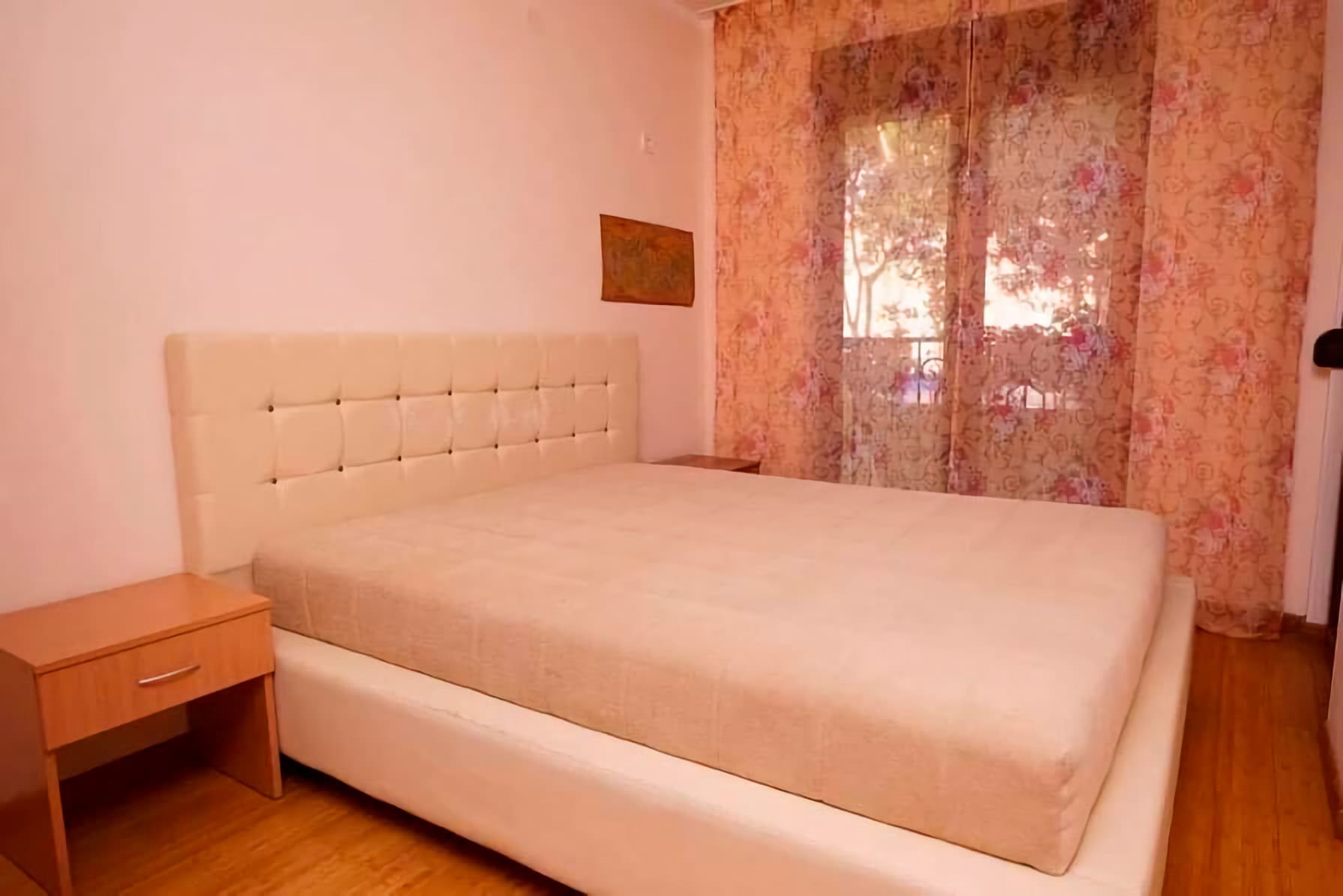 Bedroom with a double bed and bedside table in an apartment in Budva, Montenegro, with access to the balcony.