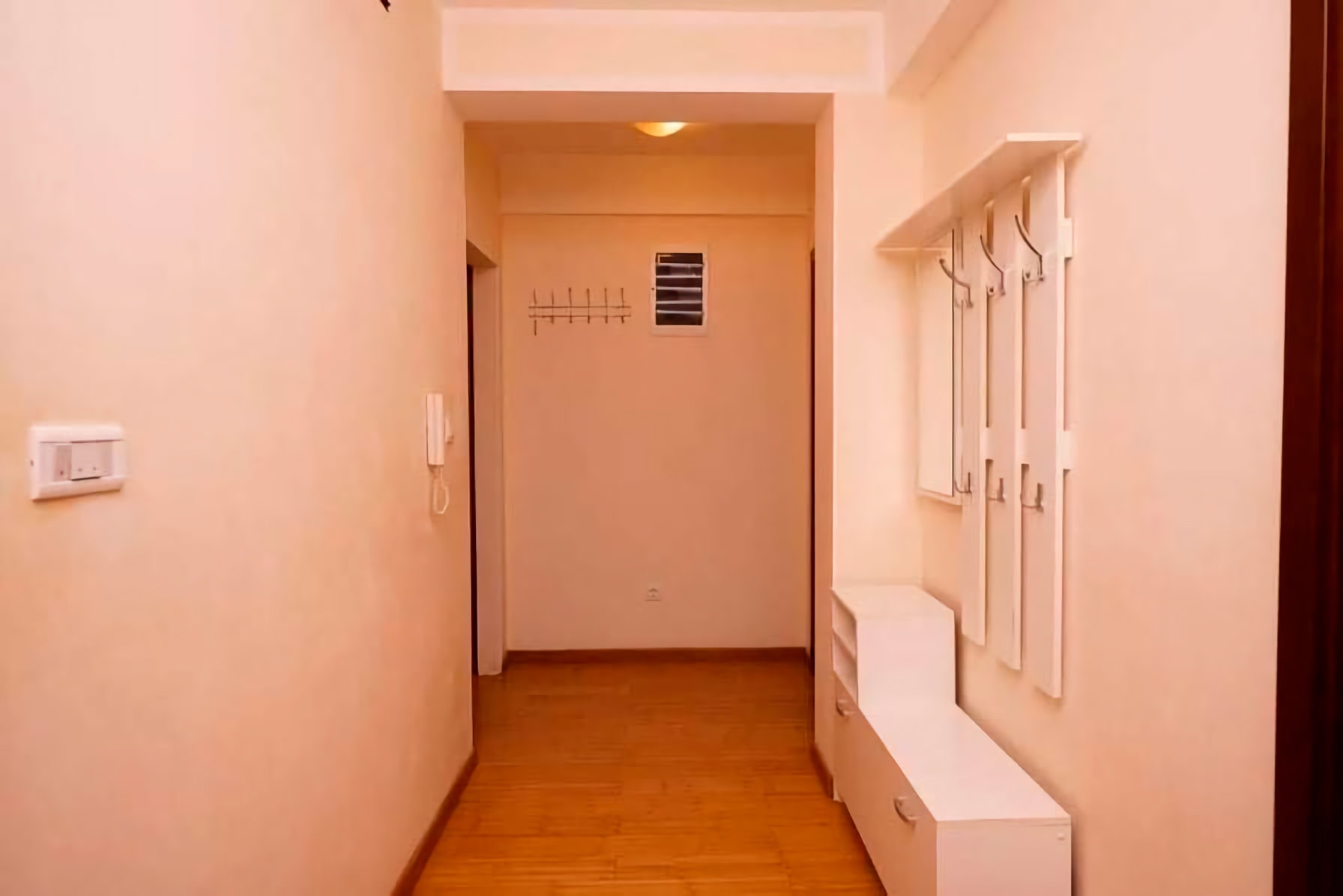 Bright hallway with white furniture and wooden flooring in an apartment for sale in Budva, Montenegro.