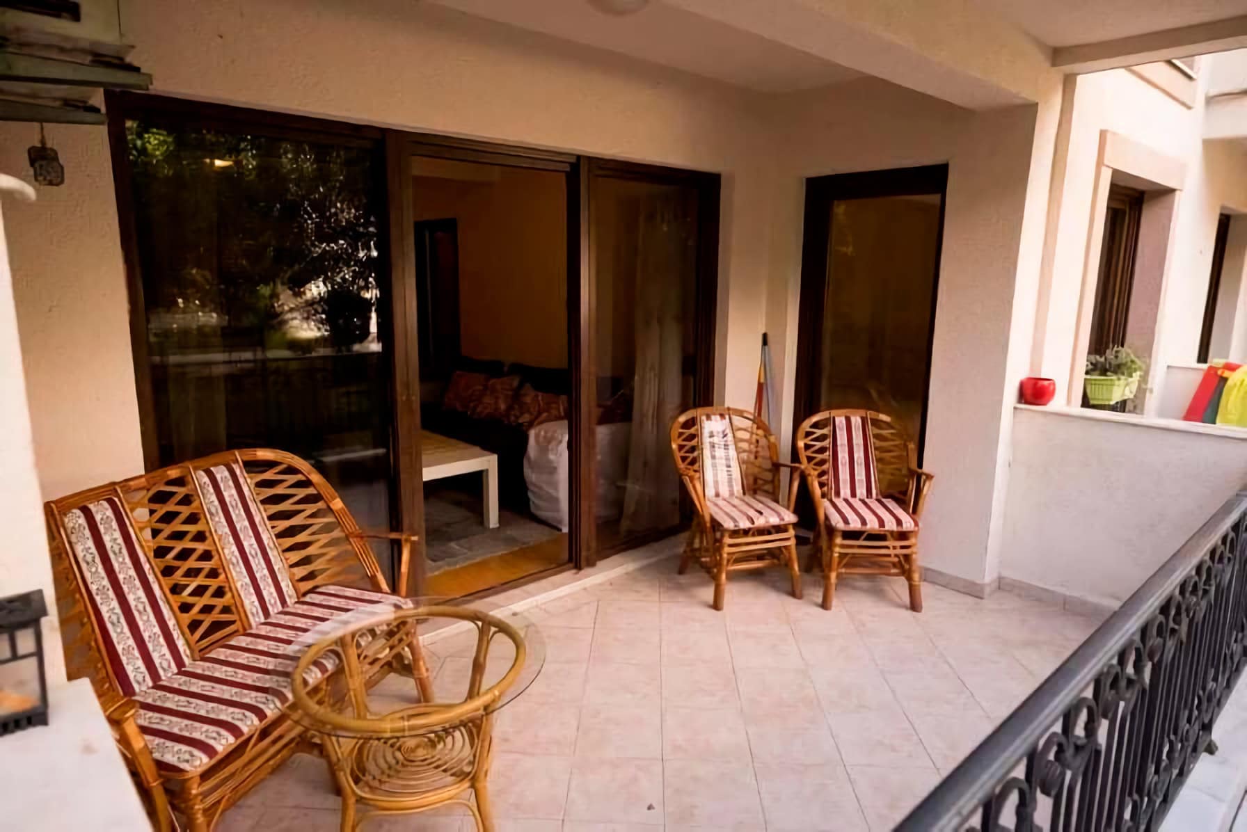 Cozy terrace with rattan furniture in an apartment in Budva, Montenegro: view of the balcony with panoramic access to the living room.