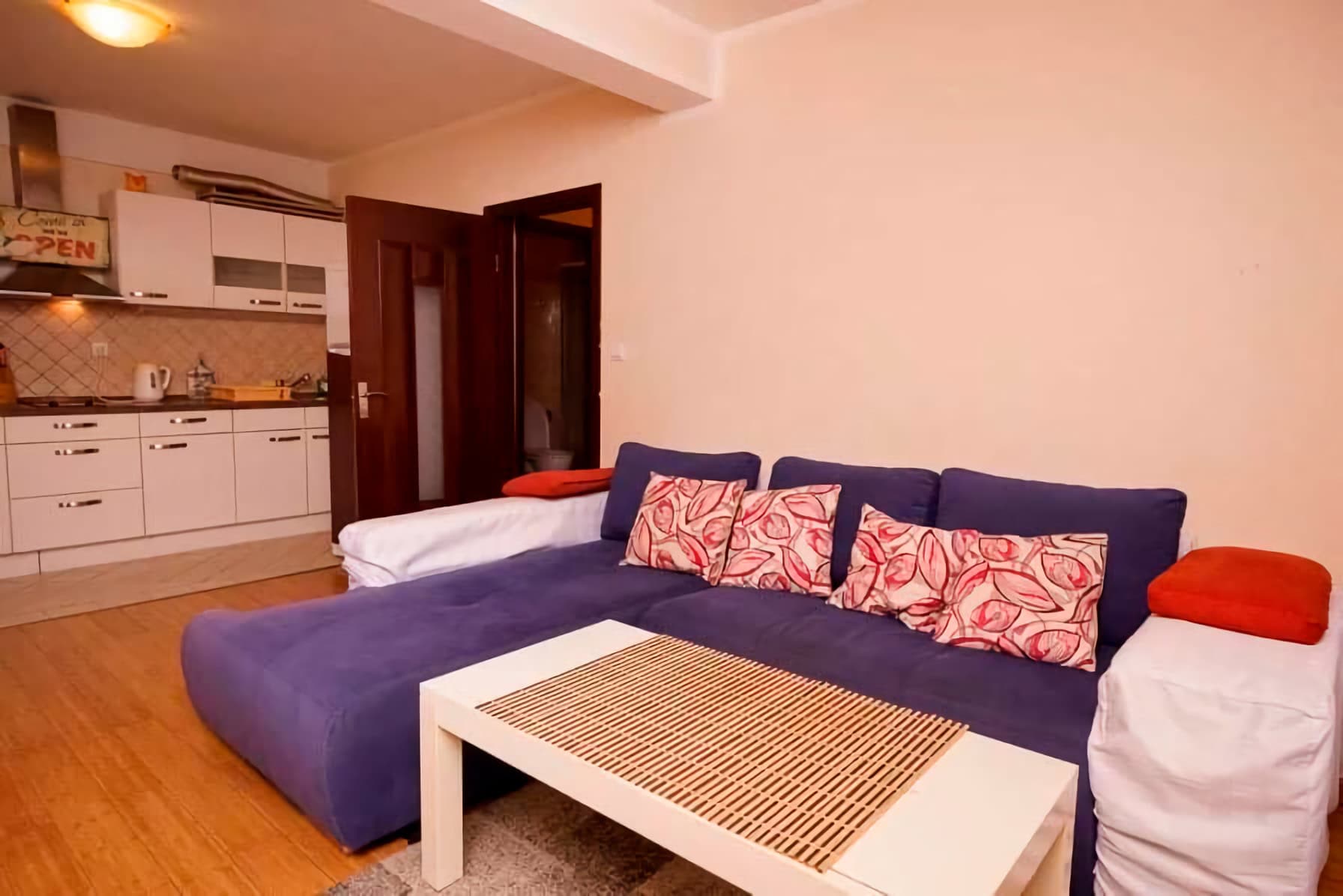 Living room with a blue corner sofa and kitchen in an apartment, Budva, Montenegro. Modern interior with white furniture.