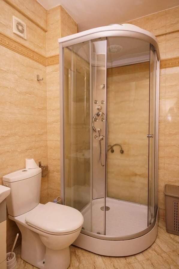 Bathroom in an apartment in Budva, Montenegro: white shower cabin and fixtures, walls finished with beige tiles.