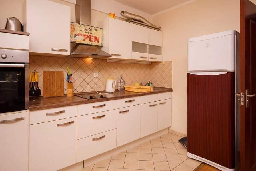 Bright kitchen with white cabinetry, built-in appliances, and a refrigerator in an apartment for sale in Budva, Montenegro.