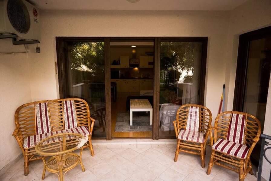 Cozy terrace with wicker furniture in an apartment in Budva, Montenegro, with access to the living room through panoramic doors.