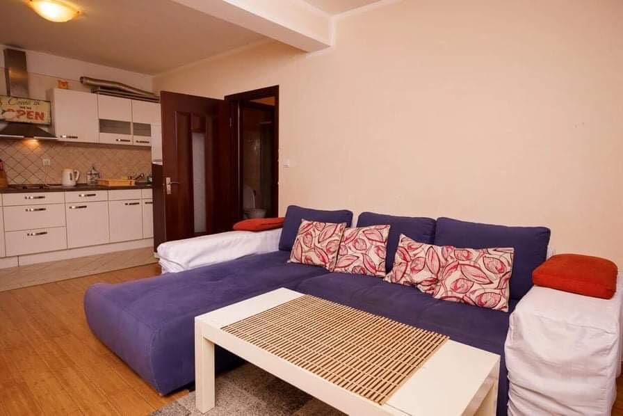 Living room with a blue corner sofa and kitchen in an apartment, Budva, Montenegro. Modern interior with white furniture.